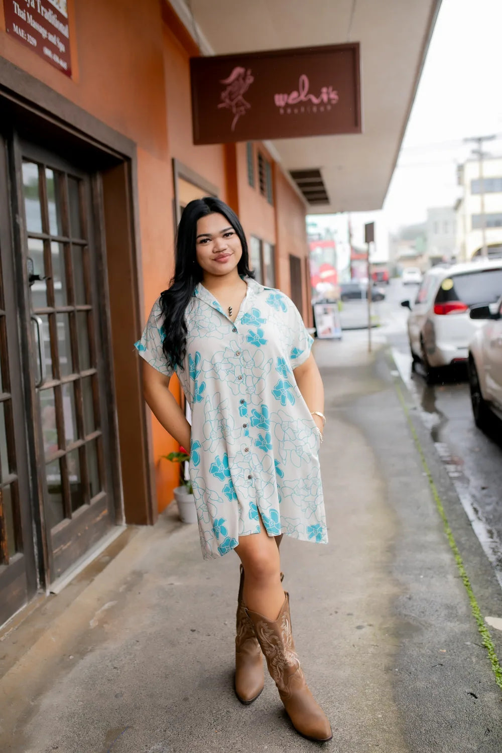 A wāhine in the cream and teal Puakenikeni print, in front of the Wehi's Boutique storefront on Hawaiʻi Island